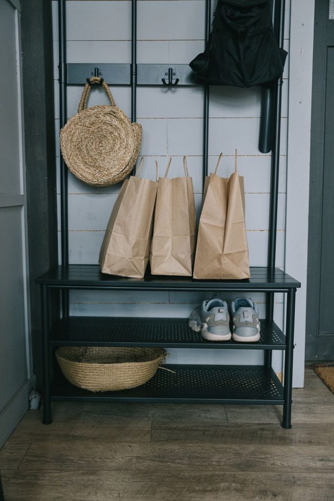 Stylish entryway featuring paper bags on a rack with casual shoes and woven decor.